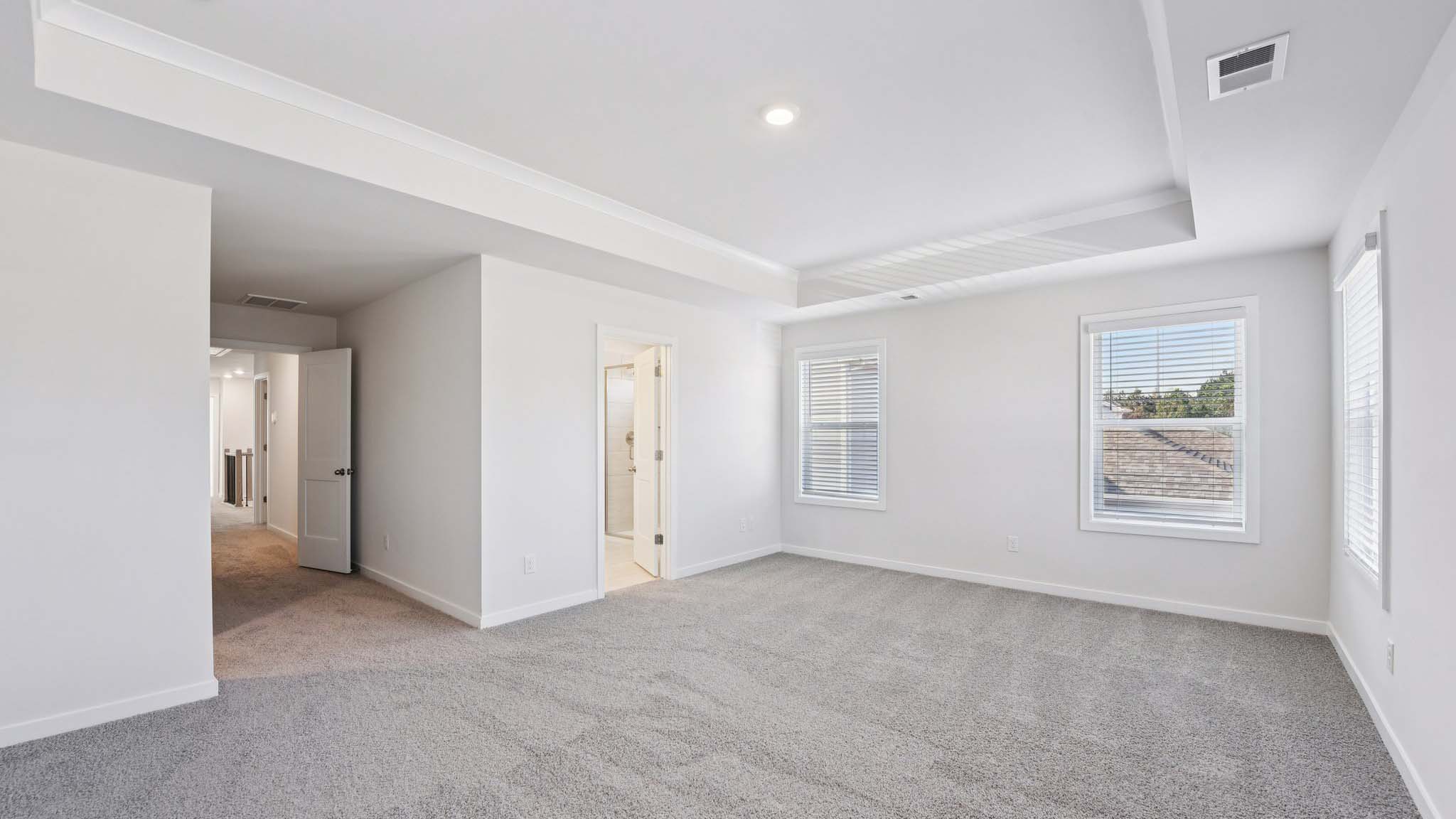 Primary carpeted bedroom with windows