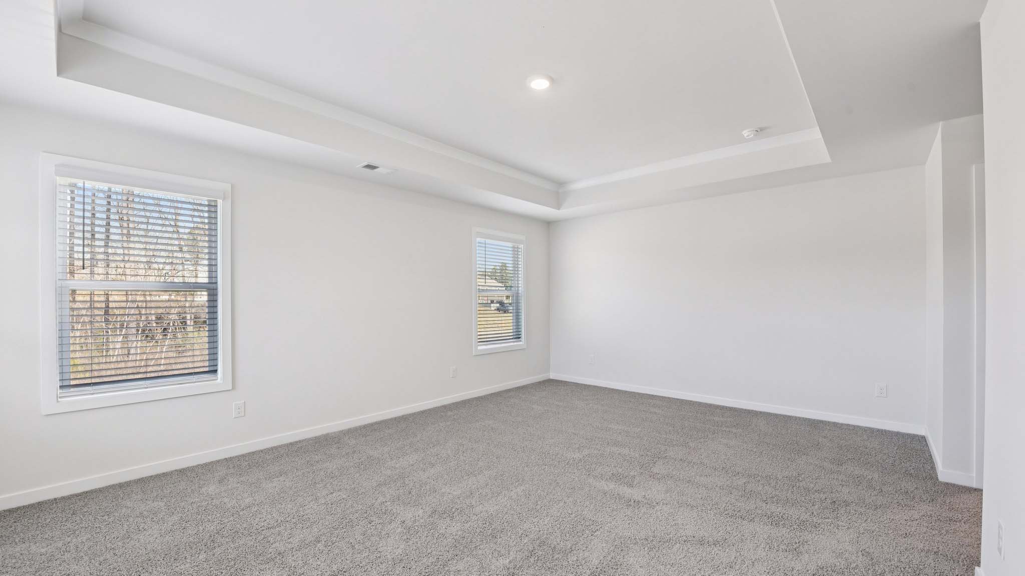 Primary carpeted bedroom with windows