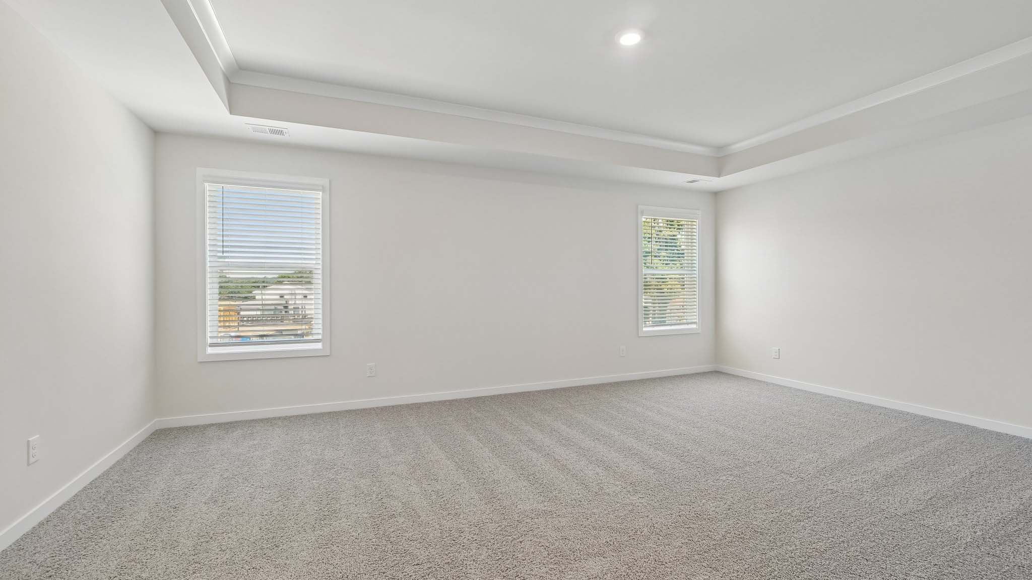 Primary carpeted bedroom with windows