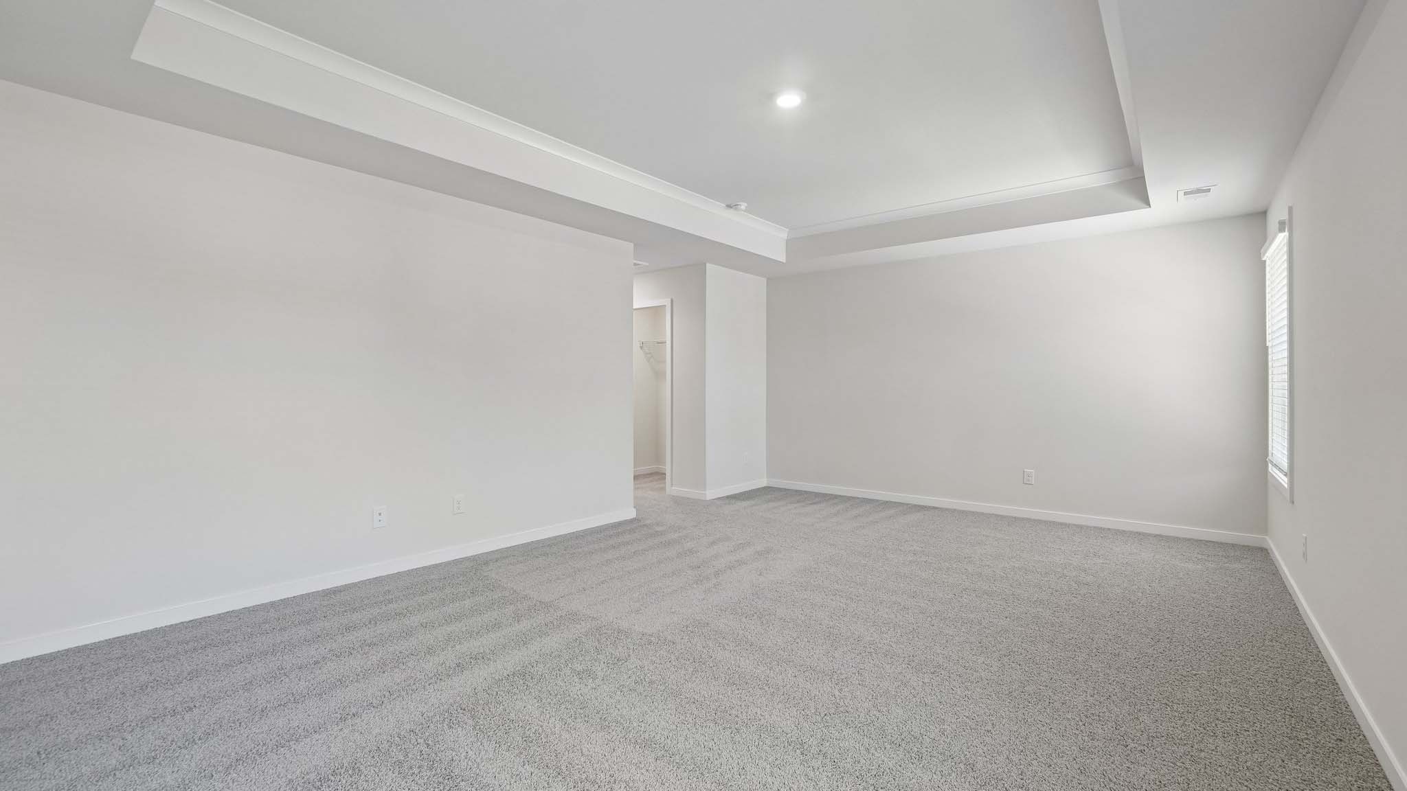 Primary carpeted bedroom with windows