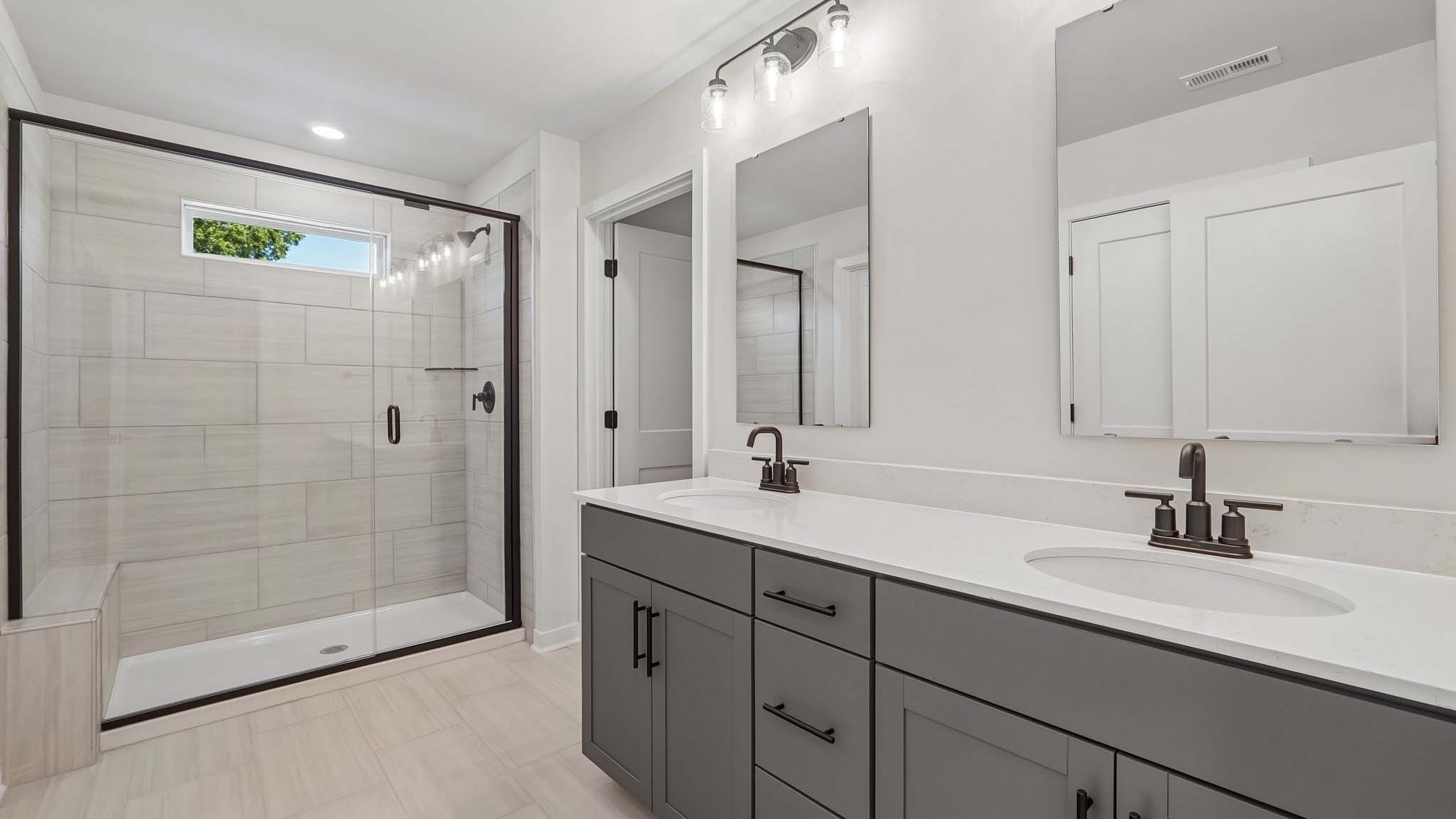 Primary bathroom with double sinks and standing glass shower