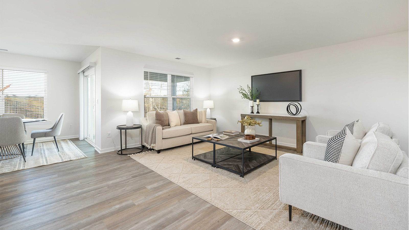 Modern open-concept living room with wood floors, and a fireplace, located beside kitchen
