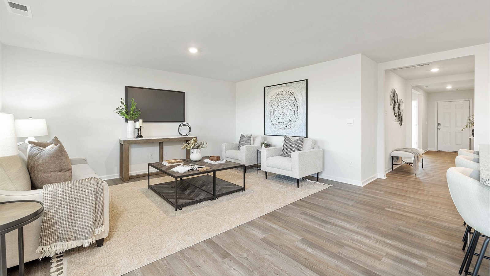 Modern open-concept living room with wood floors, and a fireplace, located beside kitchen