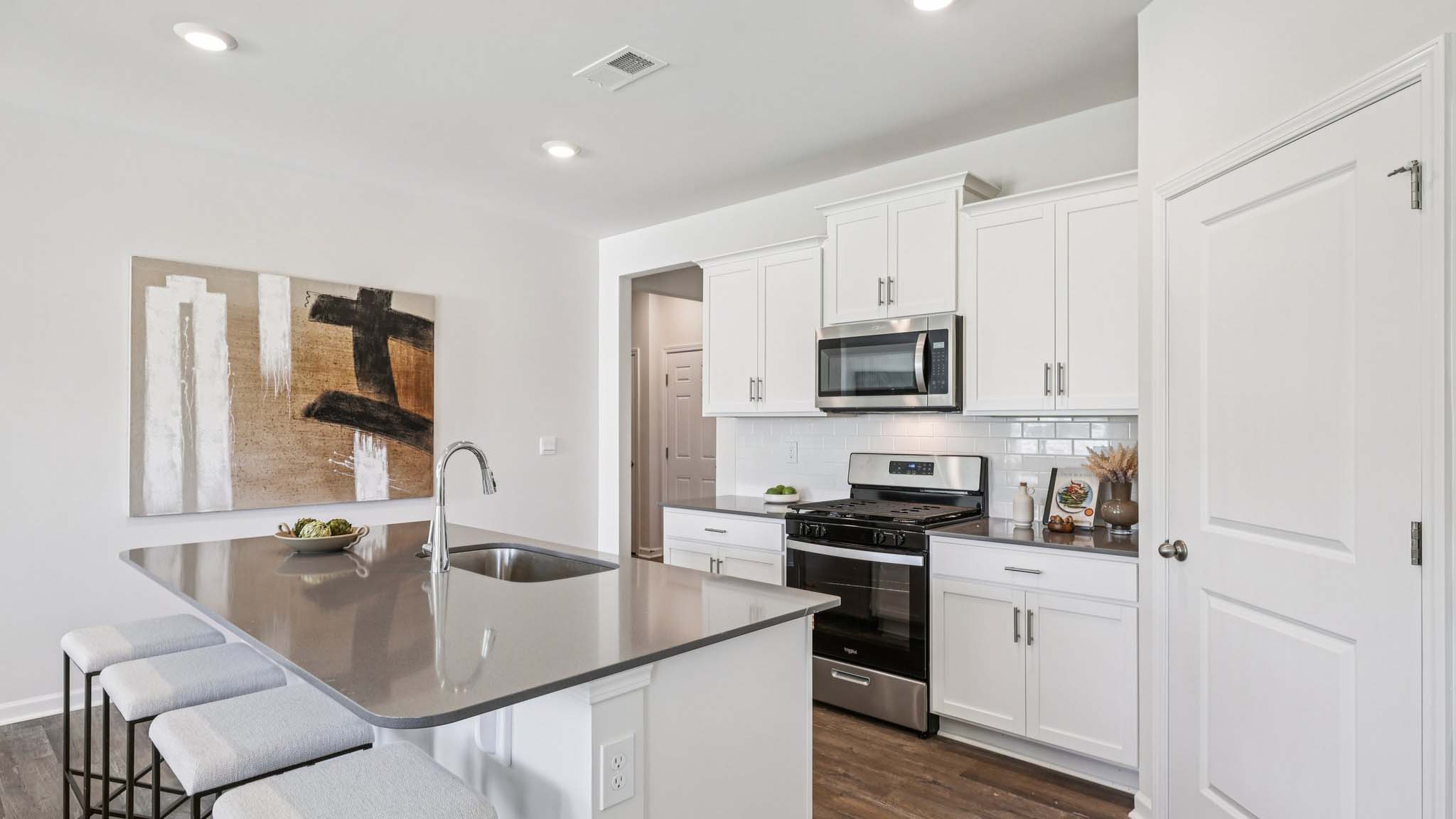 Kitchen and island with white cabinets and subway tiles and stainless steel subway tiles
