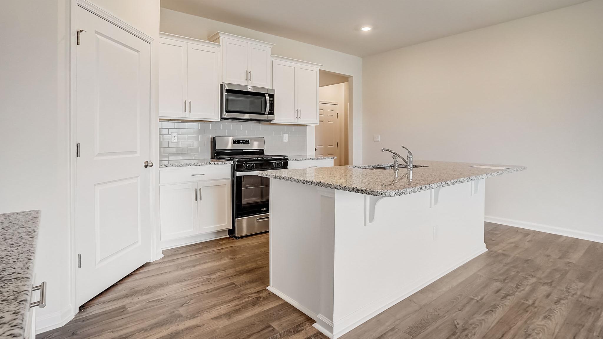 Kitchen and island with white cabinets and subway tiles and stainless steel subway tiles