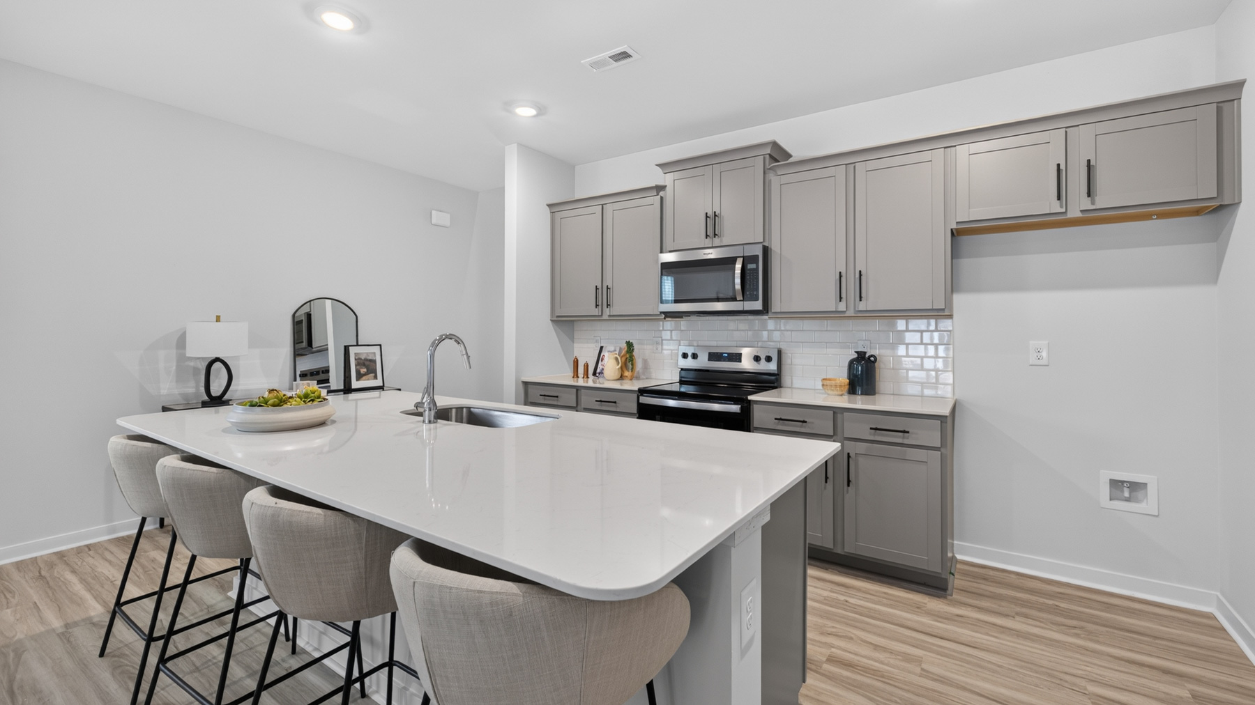 Kitchen with island, white cabinets, vinyl floors, and stainless steel appliances
