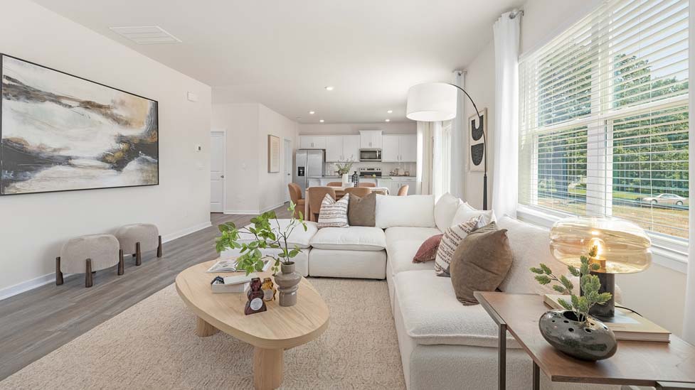 Modern open-concept living room with wood floors, and a fireplace, located beside kitchen