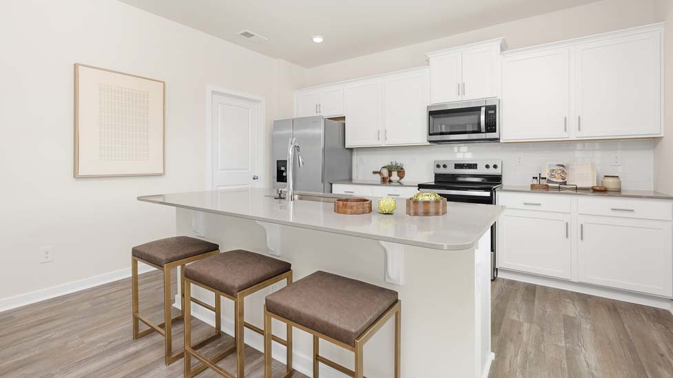 Kitchen and island with white cabinets, quarts countertops, wood floors, and stainless steel appliances