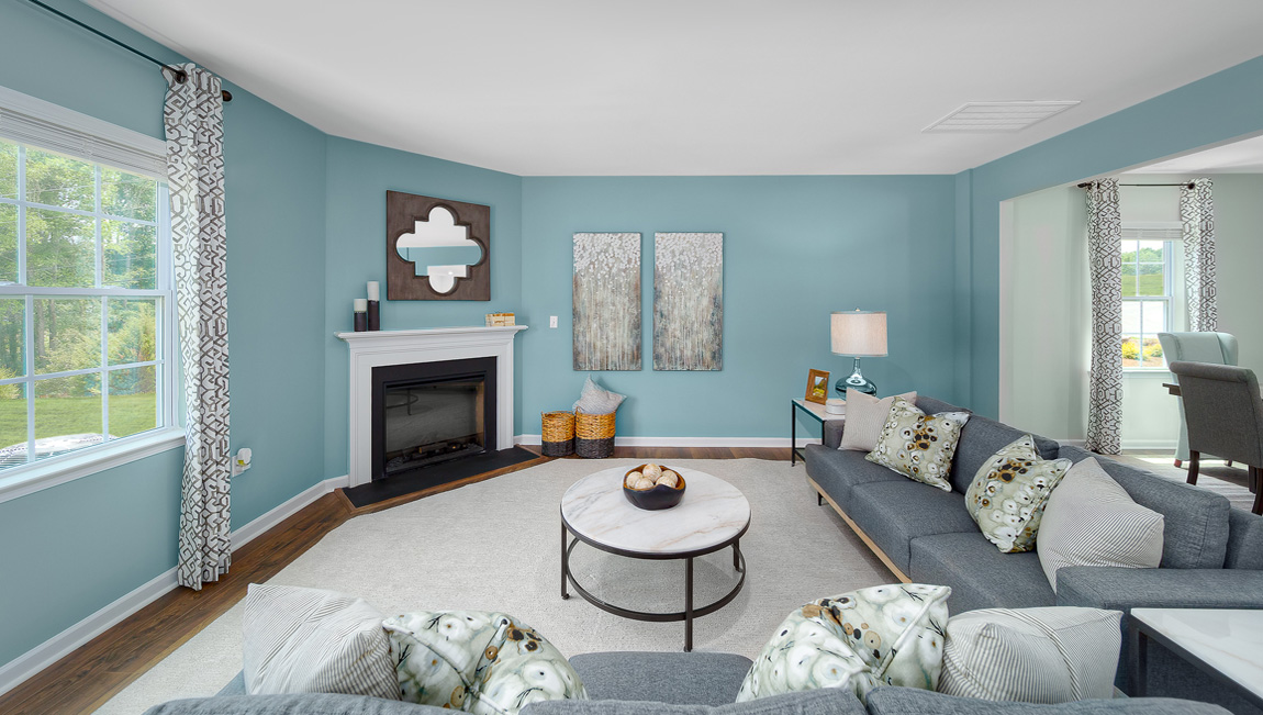 Open family room with fireplace, windows, and view of dining and kitchen