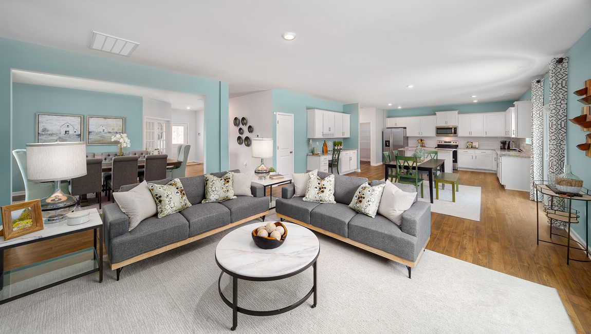 Open family room with fireplace, windows, and view of dining and kitchen