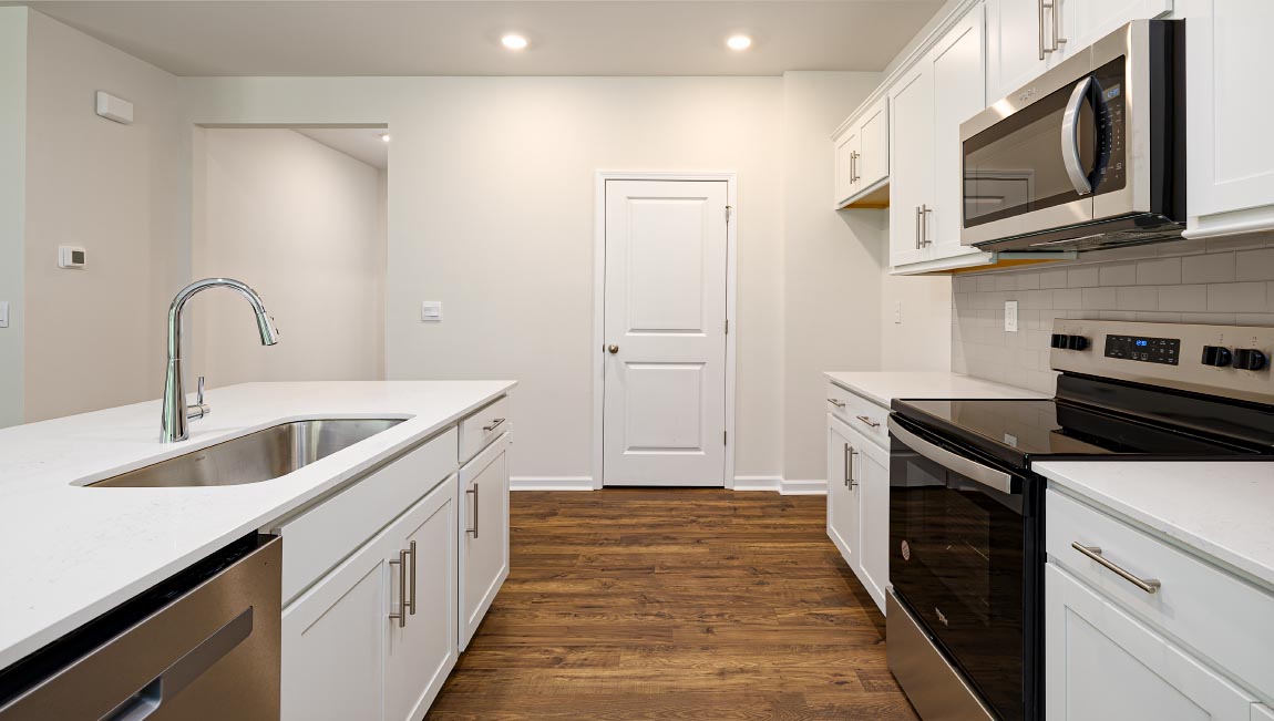 Kitchen and island with white cabinets and subway tiles and stainless steel subway tiles