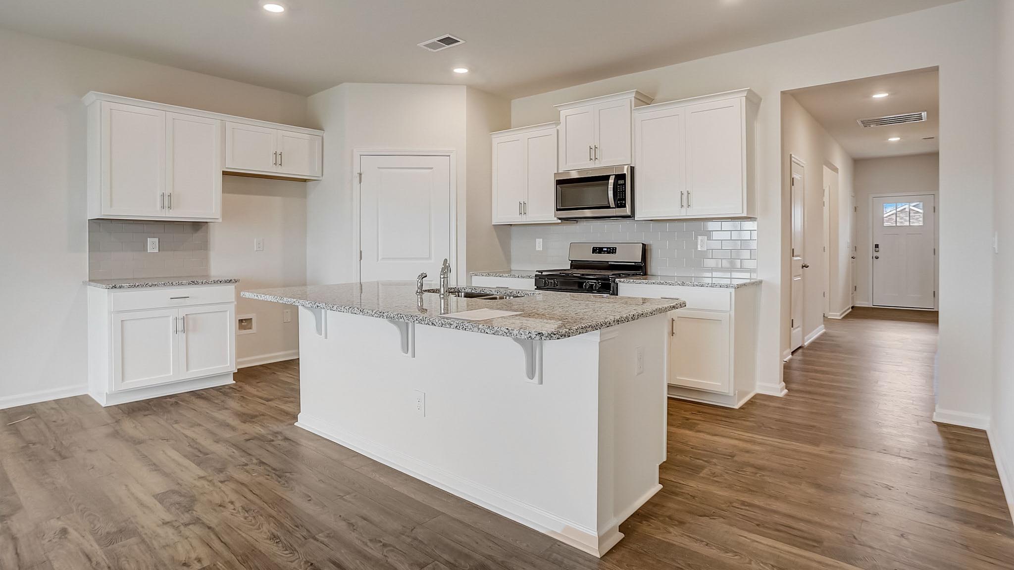 Kitchen and island with white cabinets and subway tiles and stainless steel subway tiles