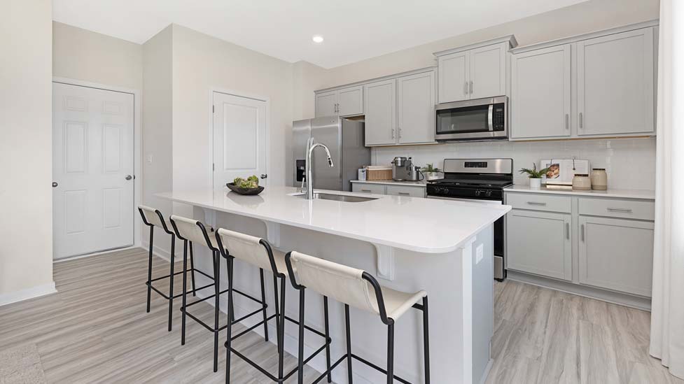 Kitchen and island with white cabinets and counters, vinyl floors and stainless steel appliances