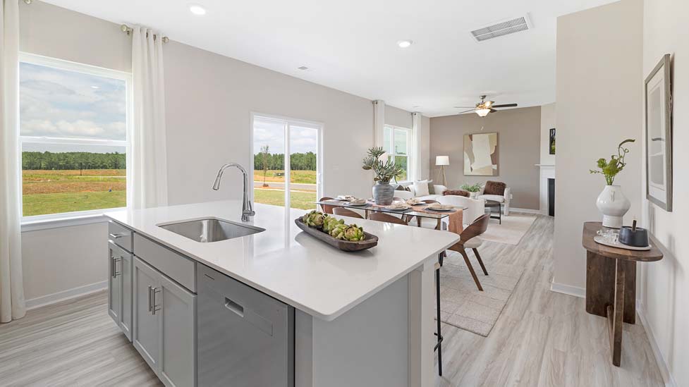 Kitchen and island with white cabinets and counters, vinyl floors and stainless steel appliances
