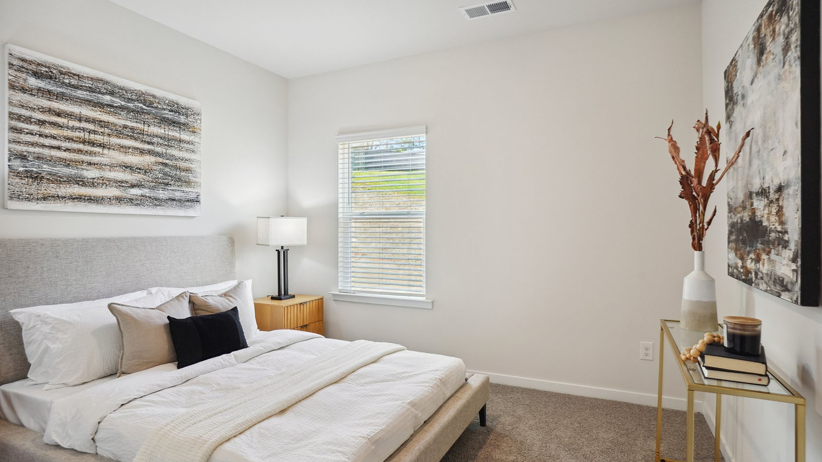 Model primary carpeted bedroom with large window