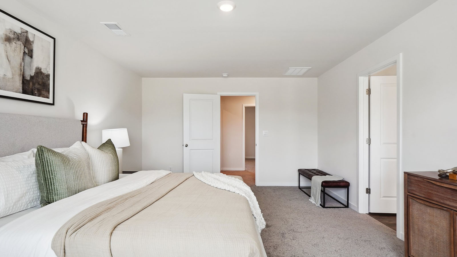 Model primary carpeted bedroom with large window