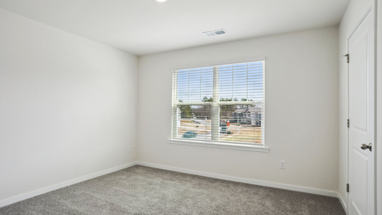 Model carpeted bedroom with small window