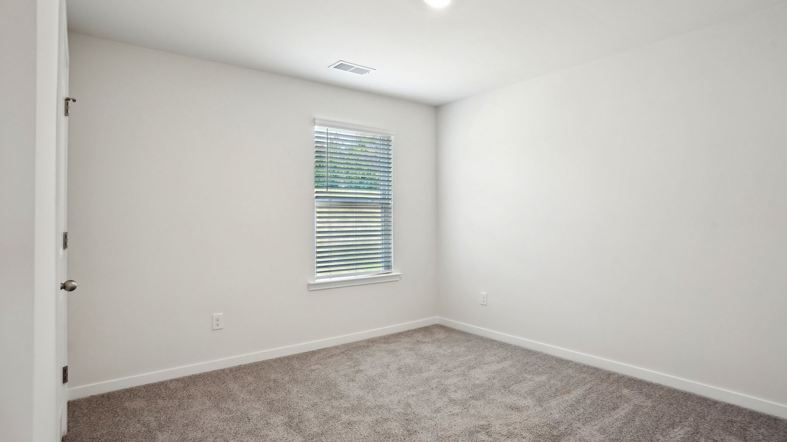 Model carpeted bedroom with small window