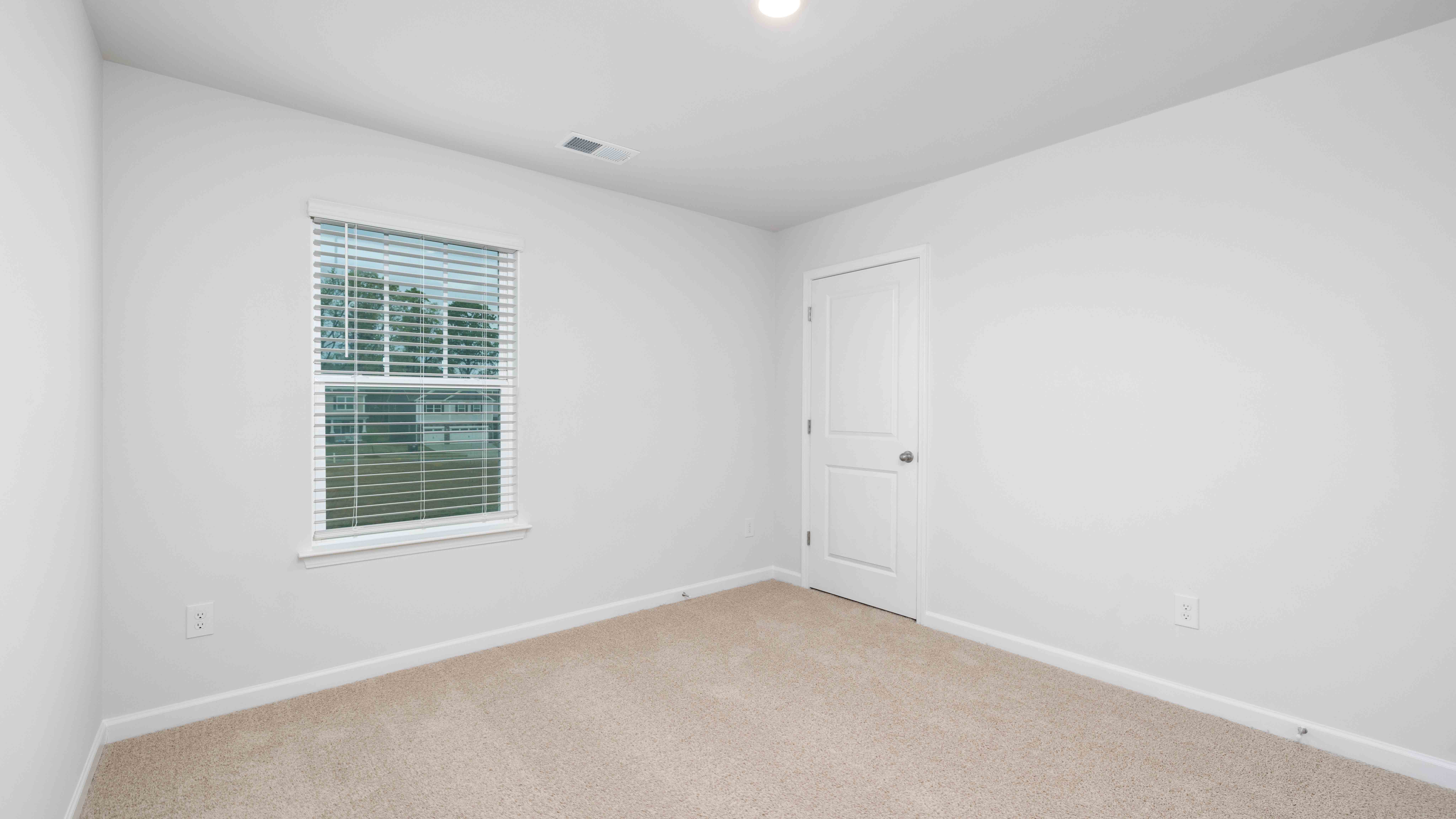 Model carpeted bedroom with small window