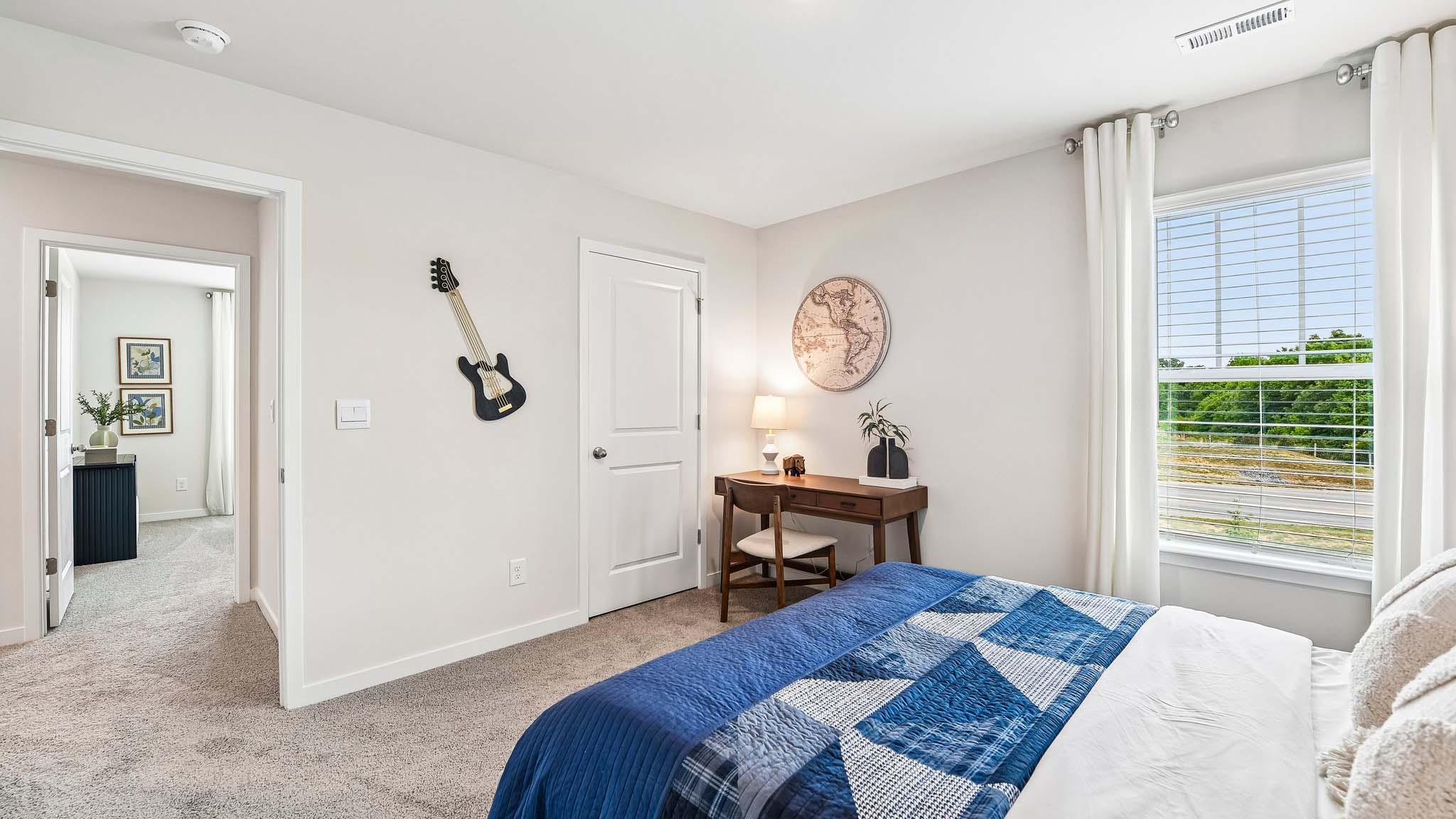 Carpeted bedroom with large window, view of bathroom door