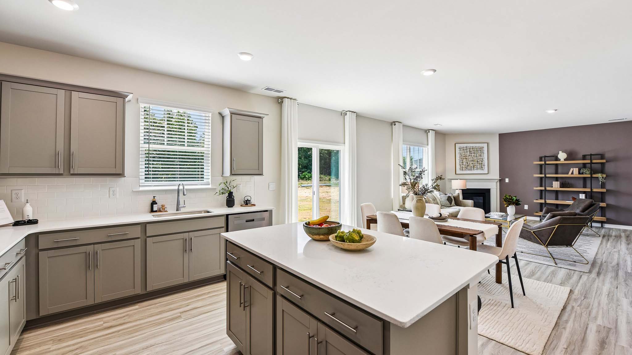 Kitchen and island with white cabinets, quartz counters, wood floors and stainless steel appliances