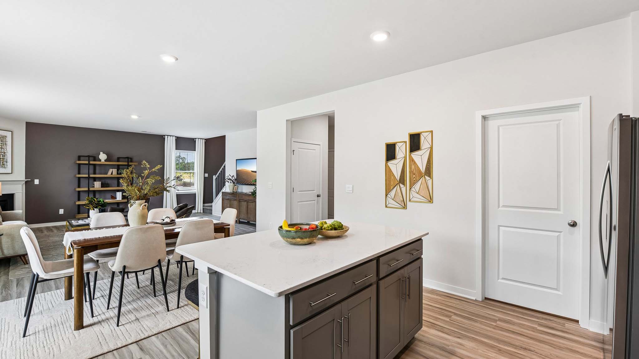 Kitchen and island with white cabinets, quartz counters, wood floors and stainless steel appliances