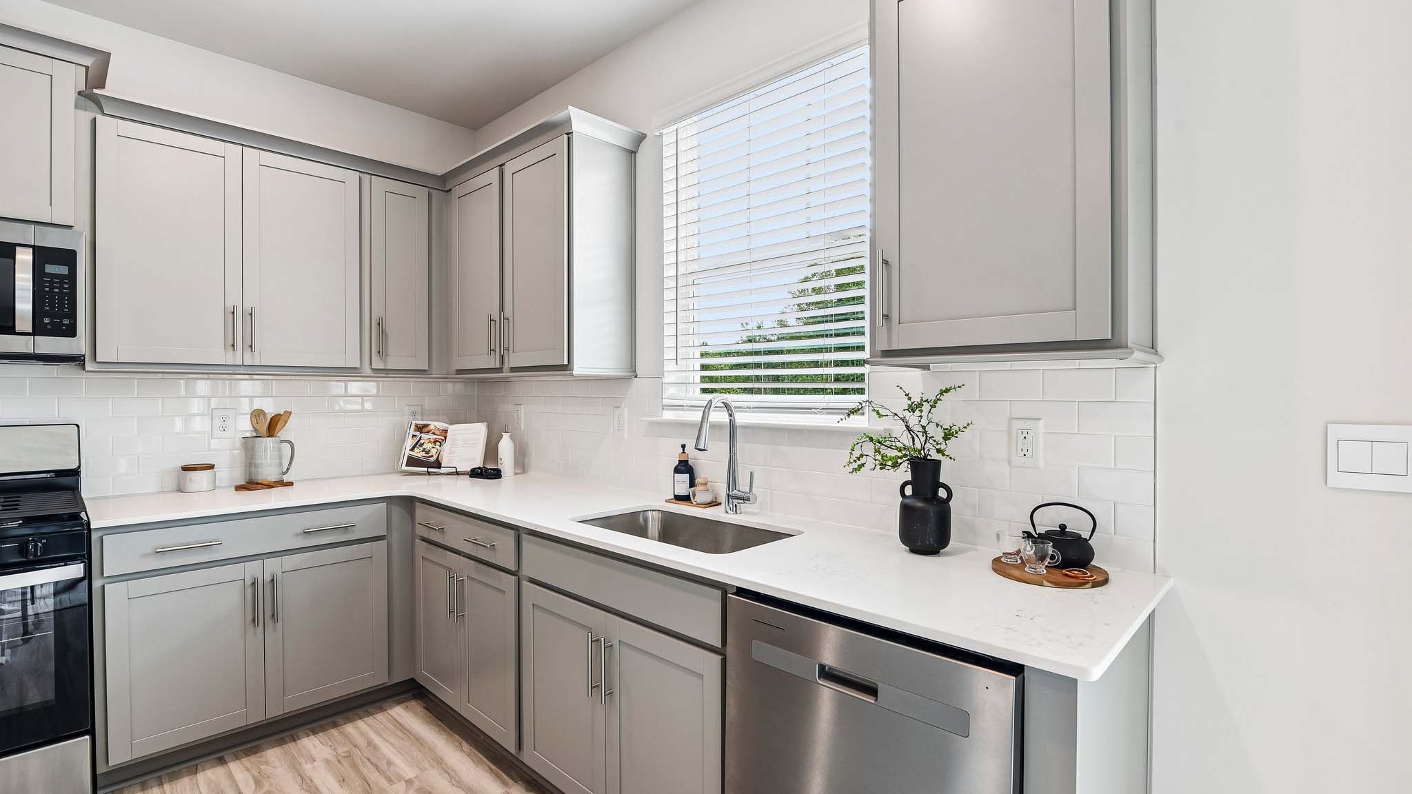 Kitchen and island with white cabinets, quartz counters, wood floors and stainless steel appliances