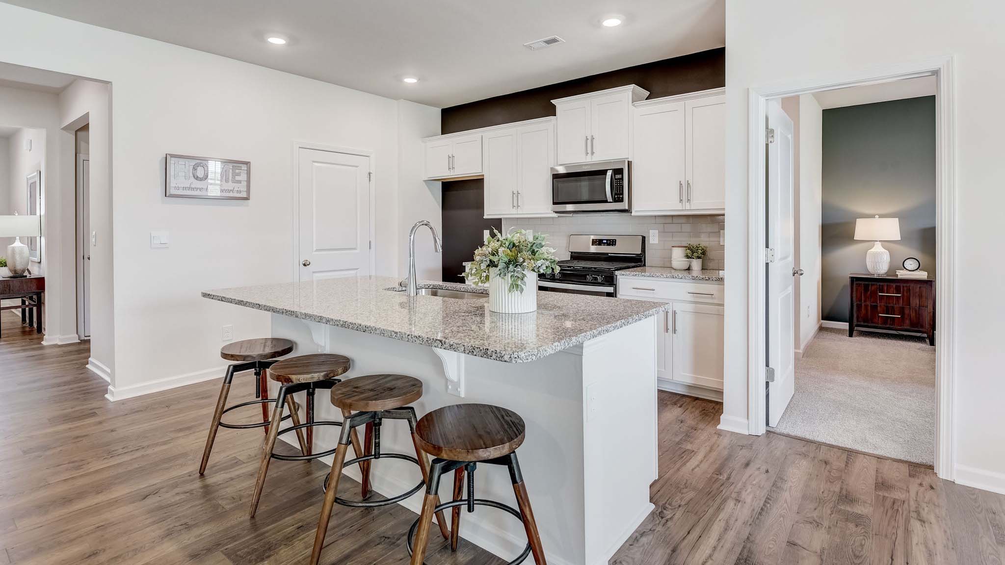 Kitchen and island with white cabinets, quarts countertops, wood floors, and stainless steel appliances