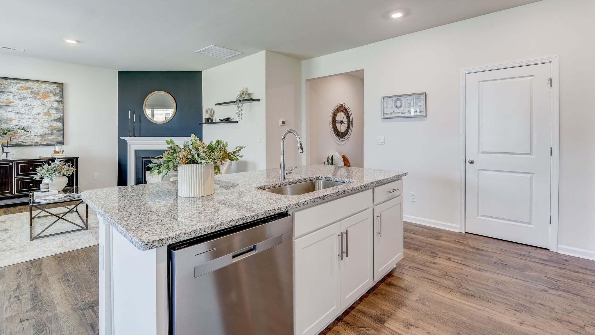 Kitchen and island with white cabinets, quarts countertops, wood floors, and stainless steel appliances