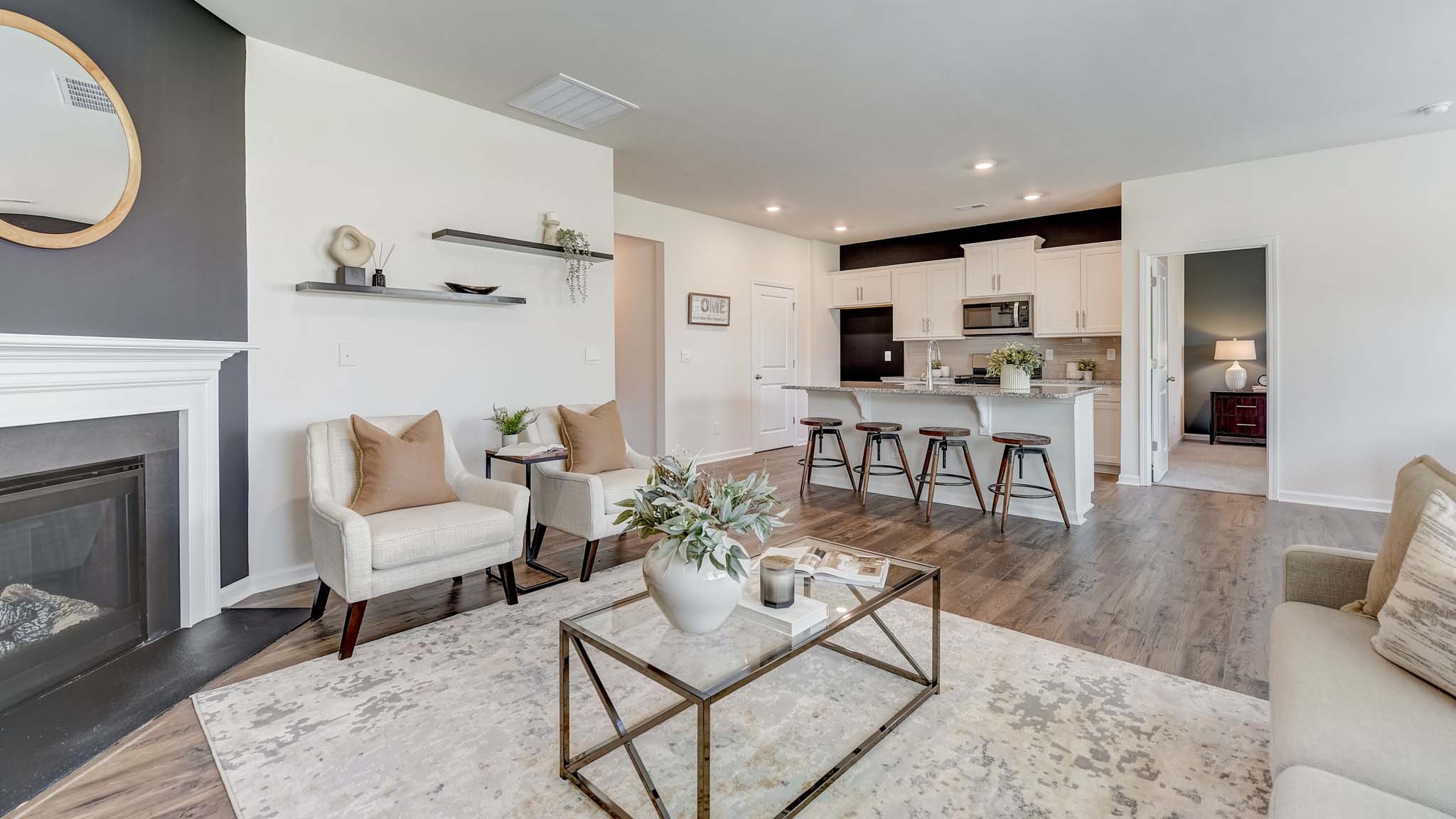 Modern open-concept living room with wood floors, and a fireplace, located beside kitchen