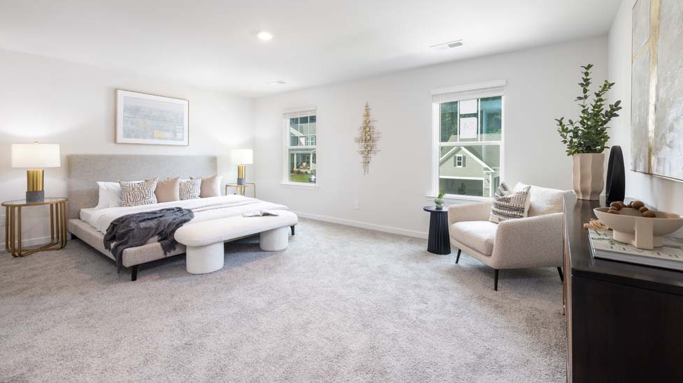 Primary bedroom with carpet and two large windows