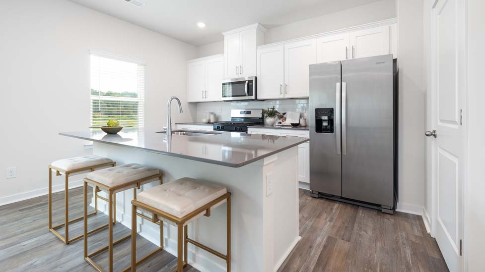 Kitchen and island with white cabinets and counters, vinyl floors and stainless steel appliances
