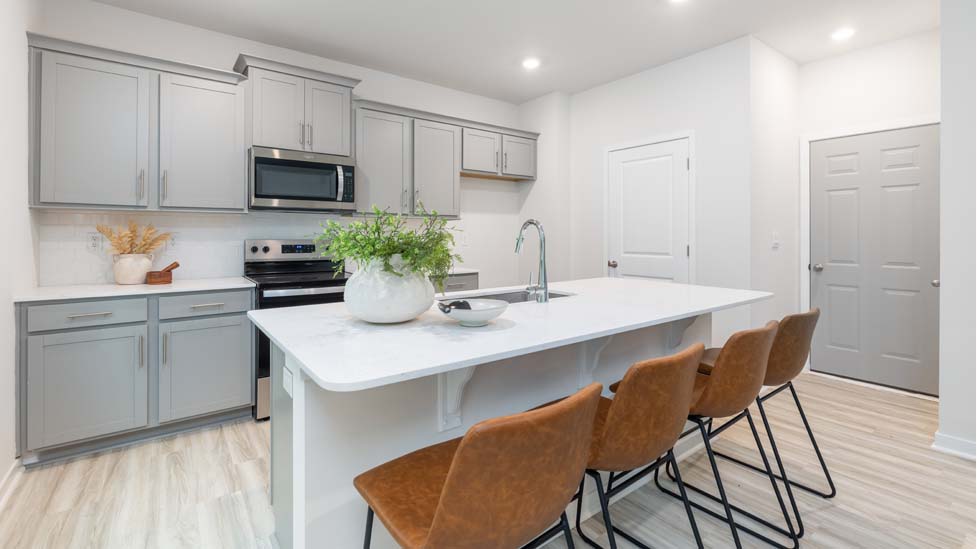 Kitchen and island with white cabinets and counters, vinyl floors and stainless steel appliances