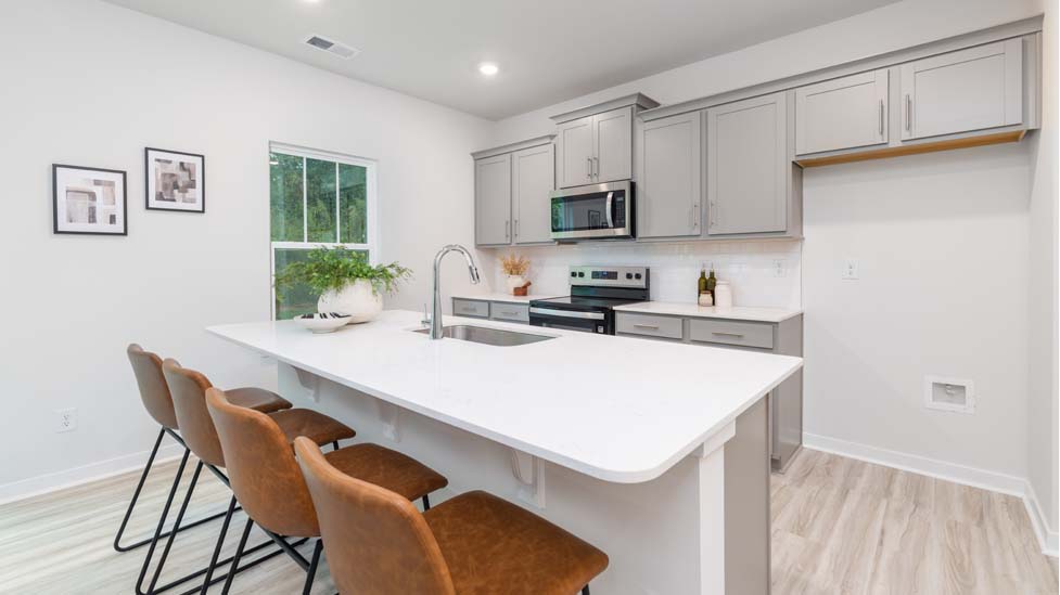 Kitchen and island with white cabinets and counters, vinyl floors and stainless steel appliances
