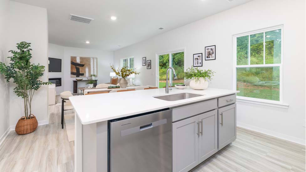 Kitchen and island with white cabinets and counters, vinyl floors and stainless steel appliances