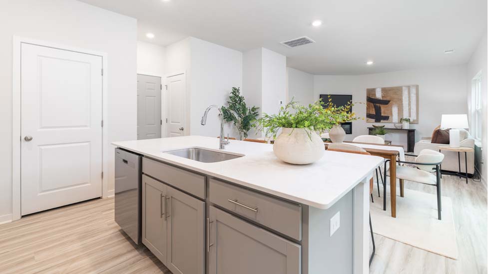 Kitchen and island with white cabinets and counters, vinyl floors and stainless steel appliances