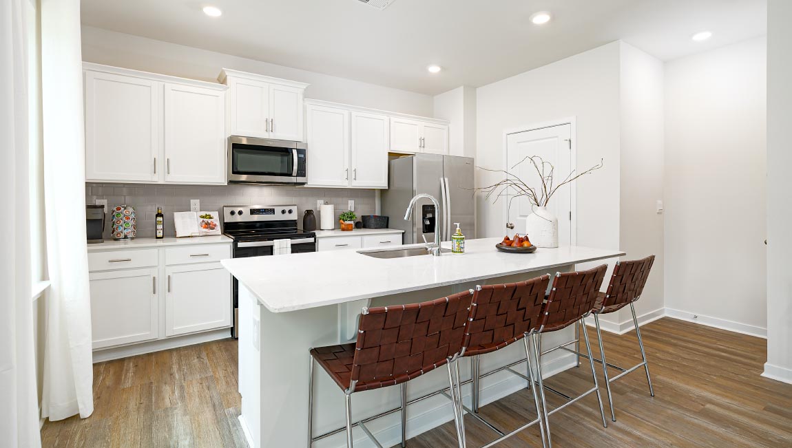 Kitchen and island with white cabinets and counters, vinyl floors and stainless steel appliances