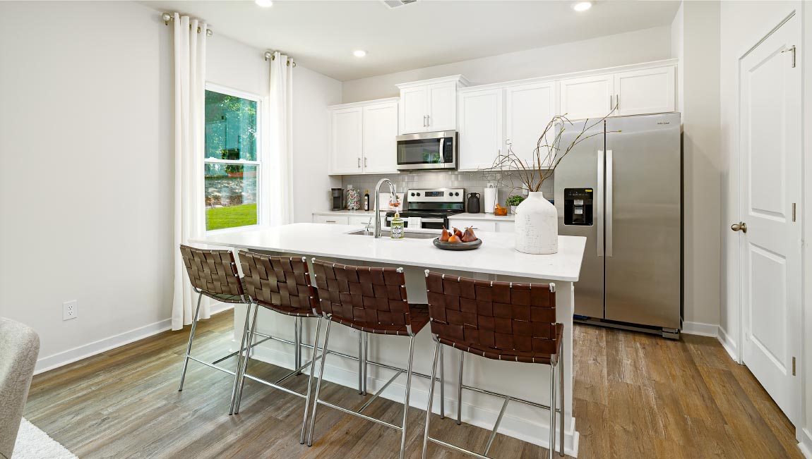 Kitchen and island with white cabinets and counters, vinyl floors and stainless steel appliances