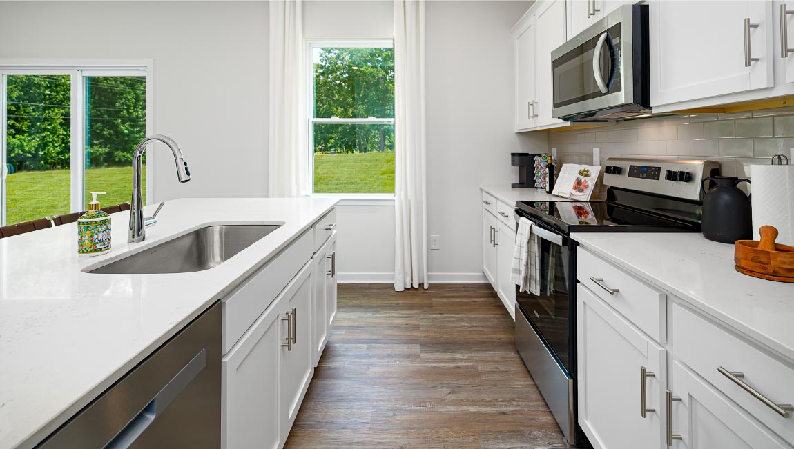 Kitchen and island with white cabinets and counters, vinyl floors and stainless steel appliances