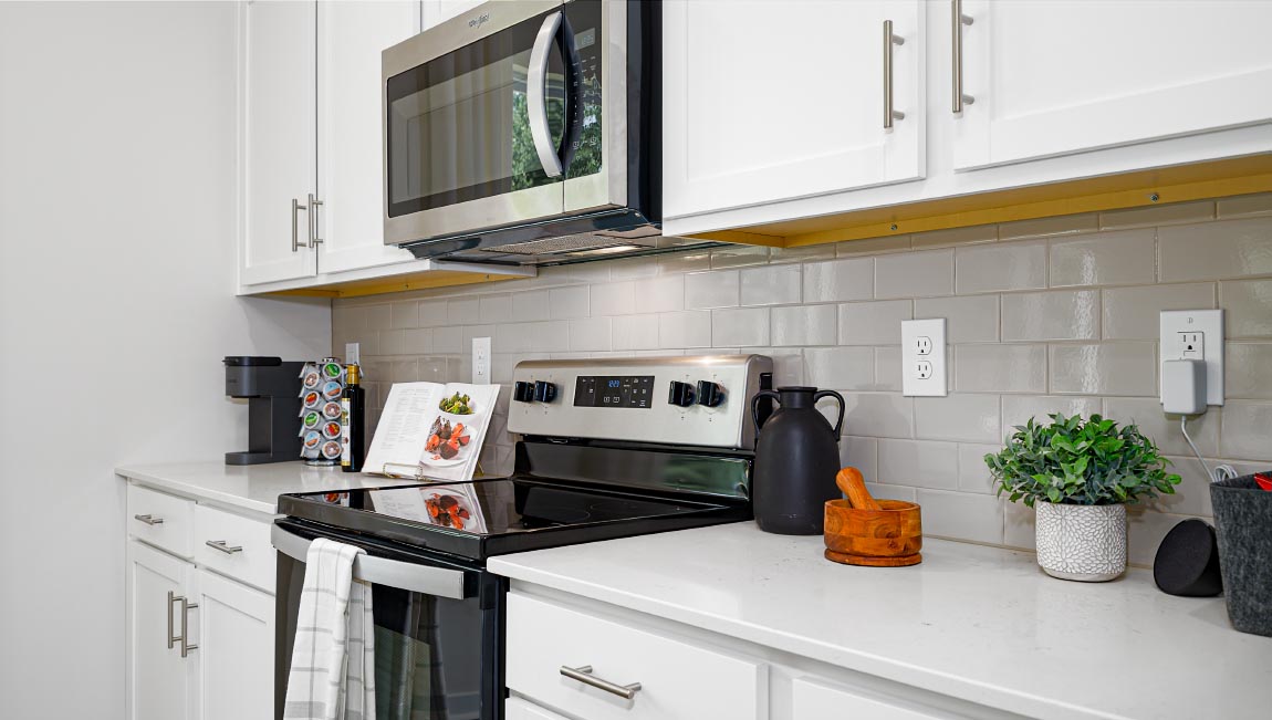 Kitchen and island with white cabinets and counters, vinyl floors and stainless steel appliances