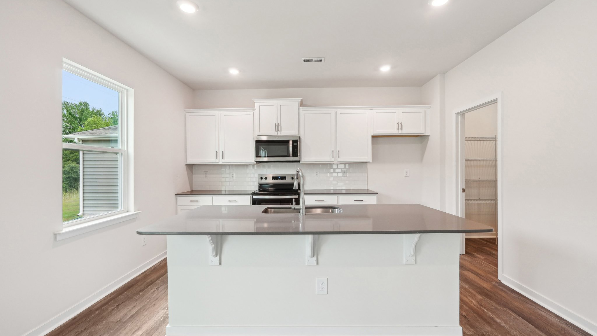 kitchen and island with large window and stainless steel appliances