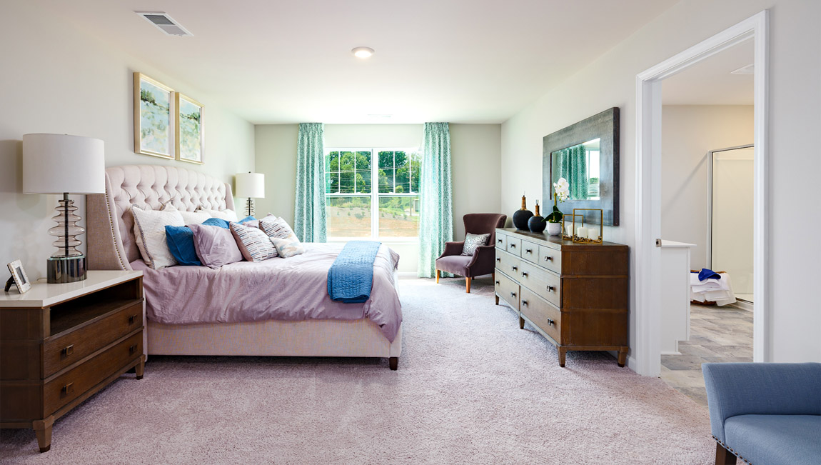 Model primary carpeted bedroom with large window