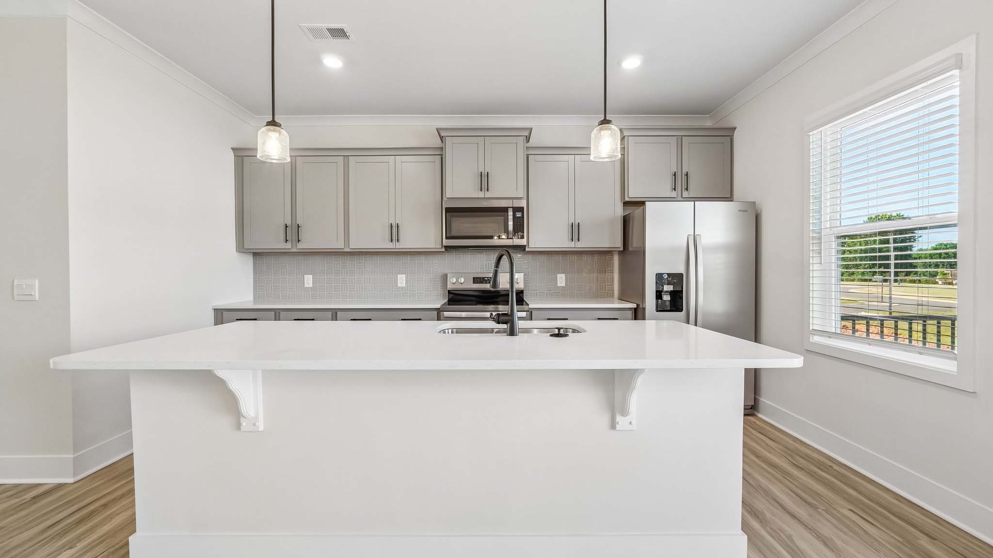 Kitchen and island with white counters and stainless steel appliances