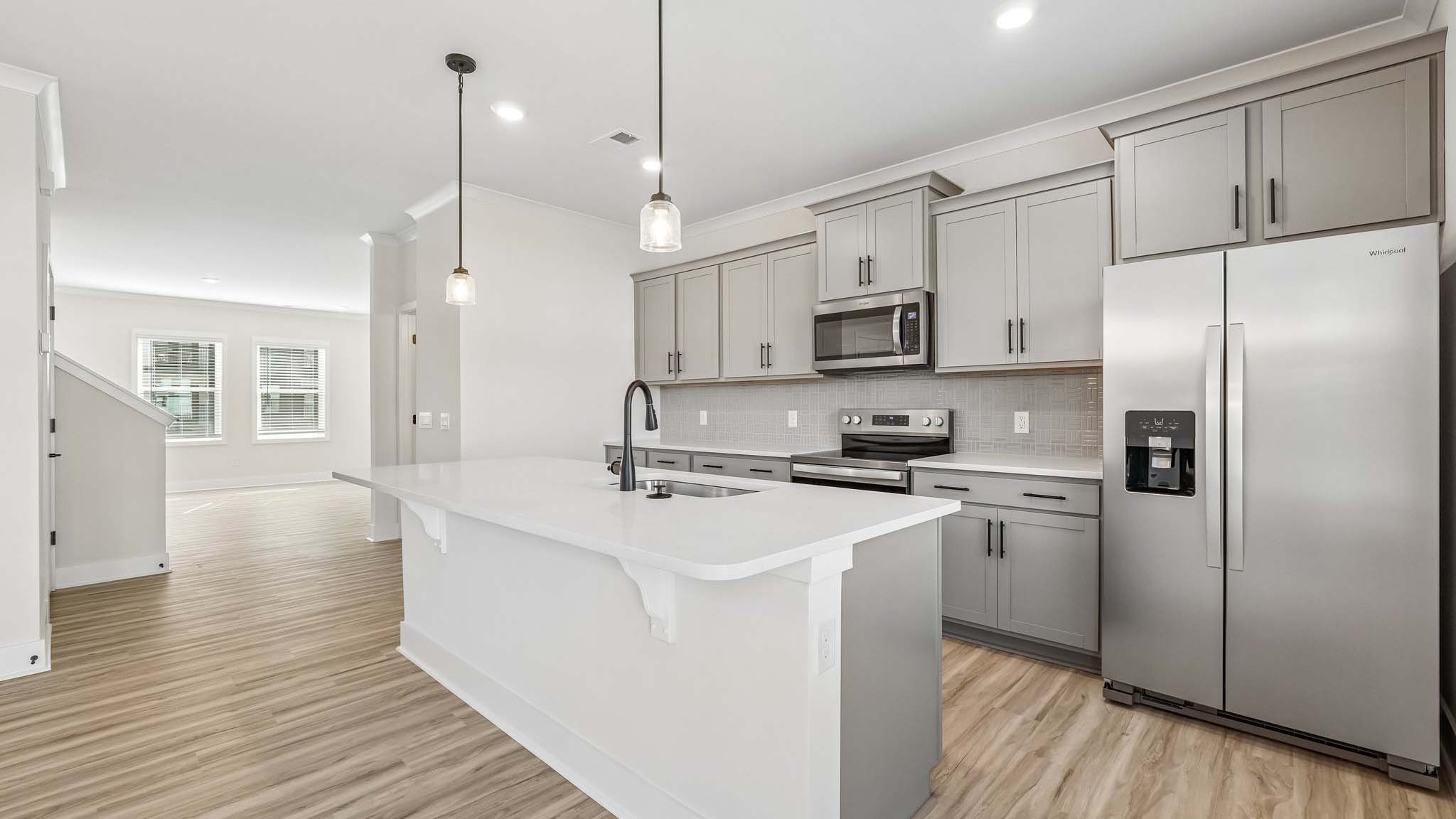 Kitchen and island with white counters and stainless steel appliances