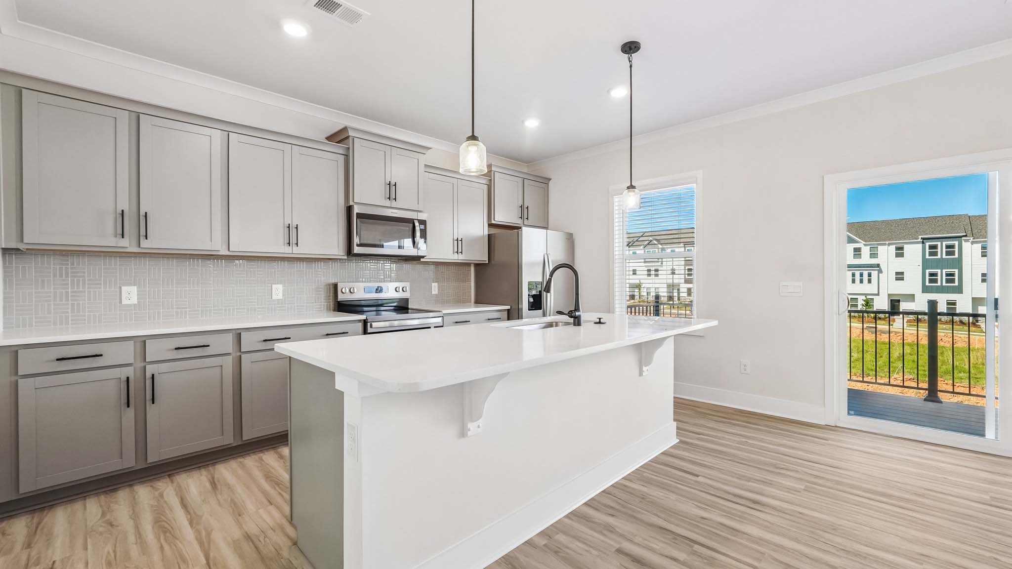 Kitchen and island with white counters and stainless steel appliances