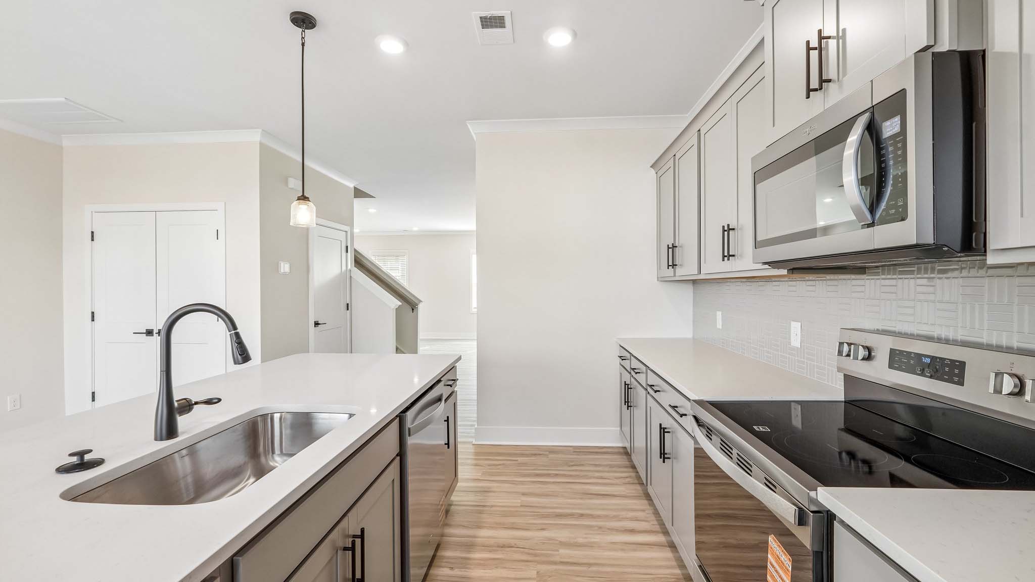 Kitchen and island with white counters and stainless steel appliances