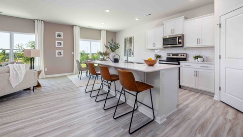 Kitchen and island with white cabinets, counters, subway tile backsplash and stainless steel appliances