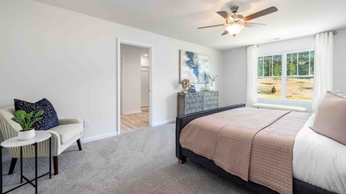 Primary bedroom with beige carpet, ceiling fan and large window