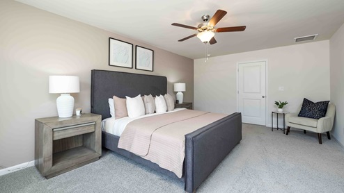 Primary bedroom with beige carpet, ceiling fan and large window