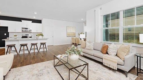 Modern open-concept living room with wood floors, and a fireplace, located beside kitchen
